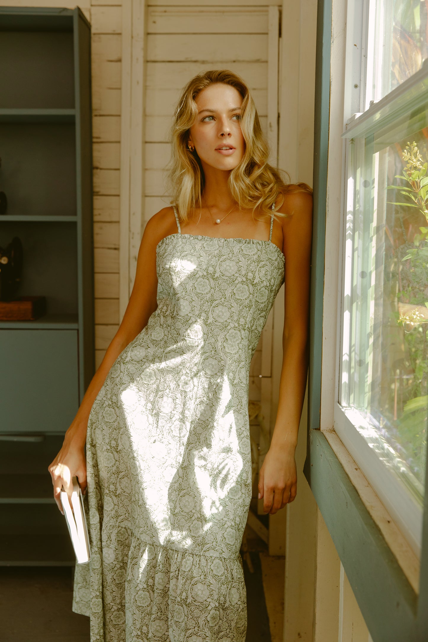 Woman leaning against a window in a green dress
