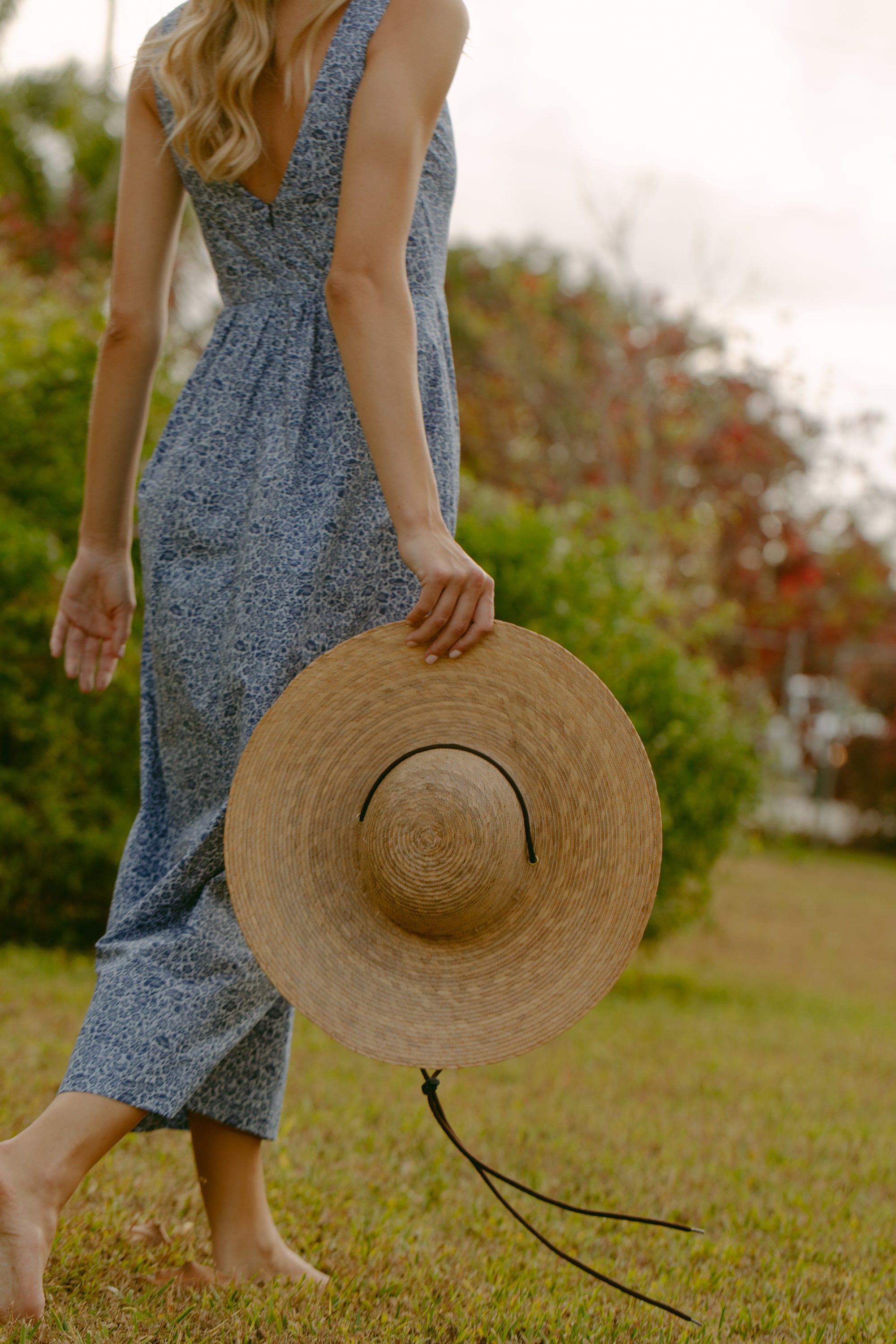 Woman walking holding a hat. 