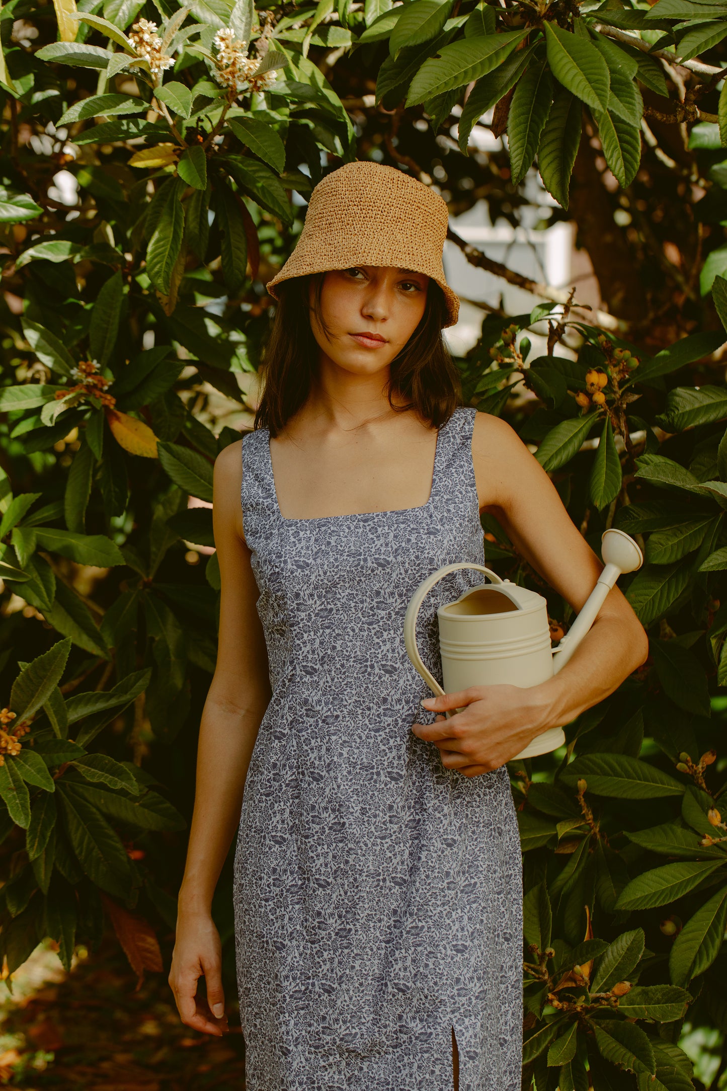 Woman holding a watering can in a blue dress