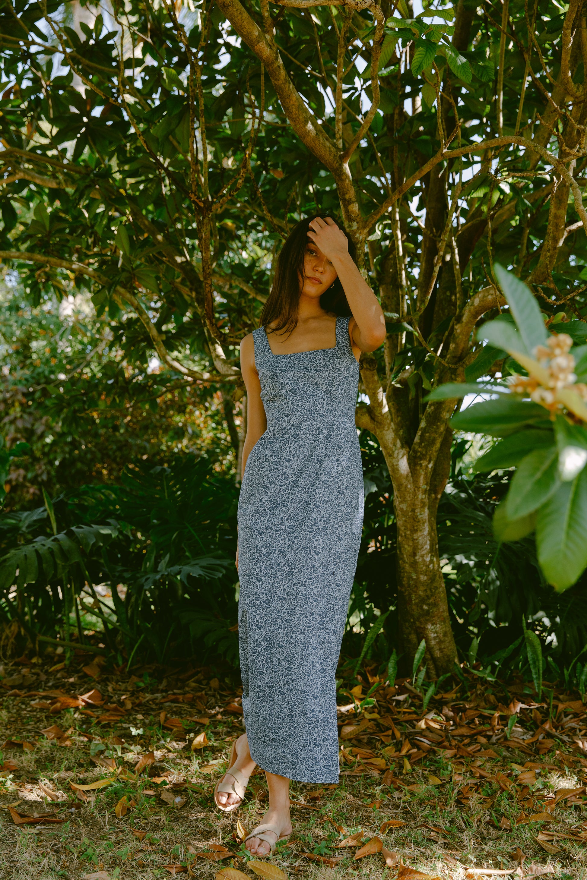 Woman leaning against a tree in a blue dress