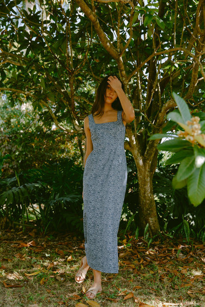 Woman leaning against a tree in a blue dress