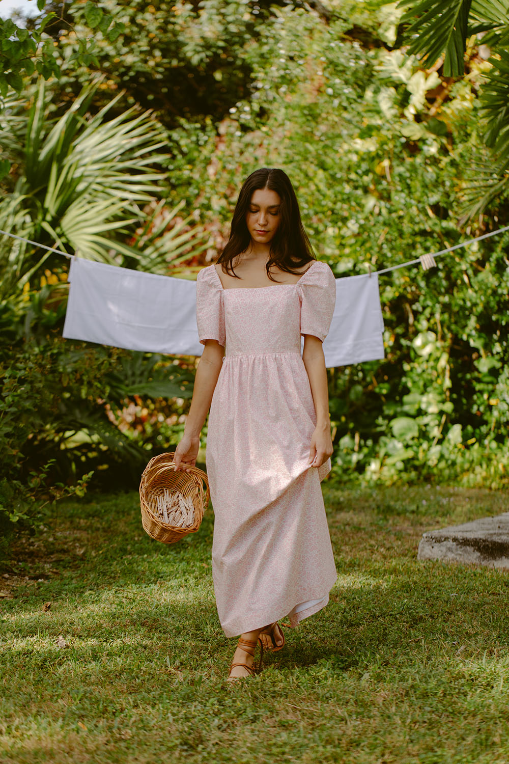 Woman wearing pink sundress by a laundry line
